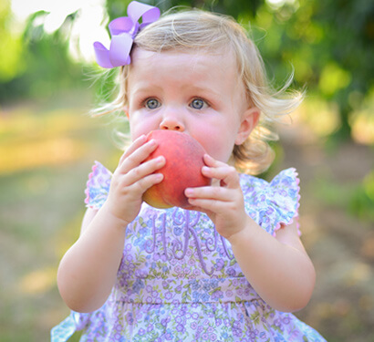 Adorable little baby enjoying a peach in Byron Georgia